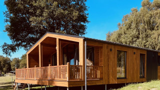Cabaña moderna de madera con amplia terraza en Lakehouse Scandi, Wilsumer Berge, Alemania, rodeada de naturaleza.