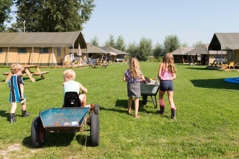Bambini giocano all'aperto a FarmCamps Oranjepolder, parco vacanze in Zelanda, Paesi Bassi.