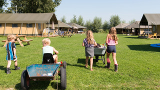 Kinderen spelen buiten bij FarmCamps Oranjepolder, een vakantiepark in Zeeland, Nederland.