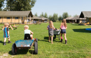 Kinderen spelen buiten bij FarmCamps Oranjepolder, een vakantiepark in Zeeland, Nederland.