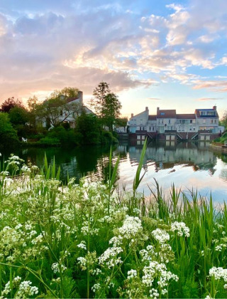 Parque de vacaciones para glamping con lago, flores silvestres y casas modernas al atardecer colorido.