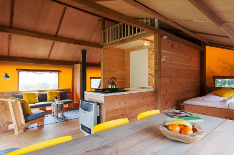Interior de tienda safari Barntent en FarmCamps BoeBaDoe, Países Bajos, con decoración de madera acogedora.