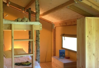 Interior de una tienda safari con litera y troncos en FarmCamps BoeBaDoe en los Países Bajos.