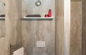 Afbeelding van een compacte badkamer in een safaritent met toilet, wastafel, plankje en bad.