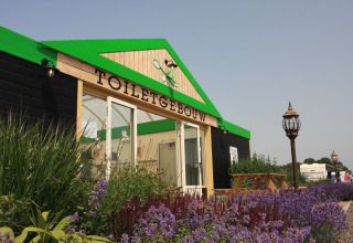 Toilettengebäude bei Boerderijcamping het Katreel, umgeben von Blumen in Overijssel, Niederlande.