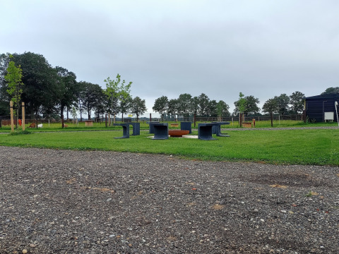Udendørs område med bænke og bålplads på Boerderijcamping het Katreel, Overijssel, Holland, under overskyet himmel.