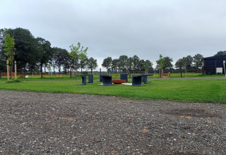 Area esterna con panche e focolare al Boerderijcamping het Katreel, Overijssel, Paesi Bassi, cielo nuvoloso.