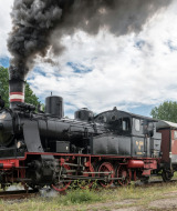 Locomotora de vapor circula por las afueras de Haaksbergen, Overijssel, Países Bajos bajo cielo nublado.