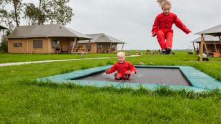 Dos niños vestidos de rojo juegan en una cama elástica en FarmCamps Kooij Hoeve, Holanda Meridional.