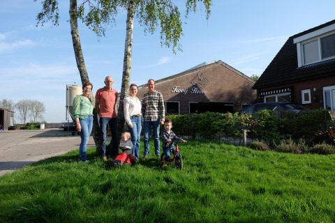 Una familia en FarmCamps Kooij Hoeve, parque vacacional en Holanda Meridional, Países Bajos, con niños en césped.