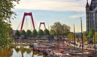 Barcos atracados en el puerto, icónico puente rojo y edificio histórico cerca de Abbenbroek, Holanda Meridional, Países Bajos.