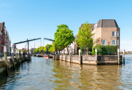 Canales y edificios históricos cerca de Abbenbroek, en Holanda Meridional, Países Bajos, con puente y cielo despejado.