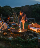 Folk sidder ved et lejrbål på Feather Down Chesters feriepark i det nordvestlige England om aftenen.