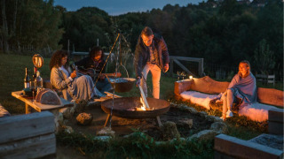 Folk sidder ved et lejrbål på Feather Down Chesters feriepark i det nordvestlige England om aftenen.