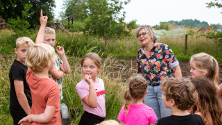 Niños y adulta participan en actividad al aire libre en FarmCamps Den Branderhorst, Gelderland, Países Bajos.