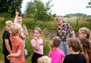 Kinderen en een volwassene doen mee aan een buitenactiviteit bij FarmCamps Den Branderhorst in Gelderland.