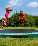 Dos niños con monos rojos saltan en una cama elástica en FarmCamps Den Branderhorst, Gelderland.