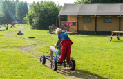 Kinder fahren spielerisch auf einem Gokart bei FarmCamps Den Branderhorst in Gelderland, Niederlande.