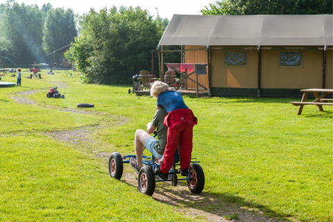 Kinder fahren spielerisch auf einem Gokart bei FarmCamps Den Branderhorst in Gelderland, Niederlande.