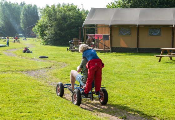 Kinder fahren spielerisch auf einem Gokart bei FarmCamps Den Branderhorst in Gelderland, Niederlande.