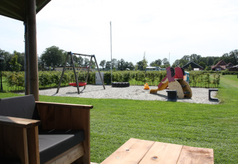 Udsigt fra terrasse mod legeplads med gynge, rutsjebane og sand, ved Farm Campsite het Katreel i Holland.