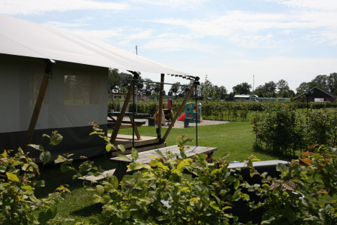 Tienda safari en Farm Campsite the Katreel con zona de juegos y vegetación en Boerderijcamping het Katreel.