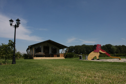 Tienda safari en el camping de granja het Katreel en los Países Bajos con área de juegos y campo abierto.