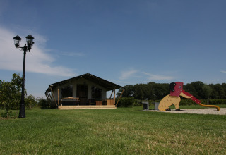 Safari-telt på Boerderijcamping het Katreel i Holland med legeplads og grønne marker under en blå himmel.