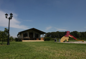 Safari-telt på Boerderijcamping het Katreel i Holland med legeplads og grønne marker under en blå himmel.