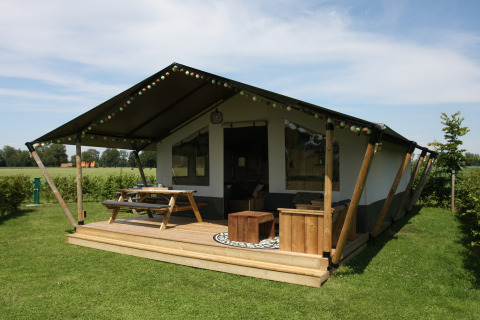 Safari-Zelt auf dem Farm Campsite the Katreel mit Holzterrasse und Picknicktisch auf grüner Wiese.