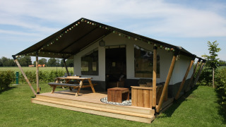 Safari-Zelt auf dem Farm Campsite the Katreel mit Holzterrasse und Picknicktisch auf grüner Wiese.