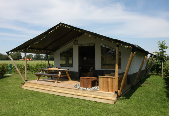 Tenda safari presso Farm Campsite the Katreel con terrazza in legno, tavolo da picnic e sedie sul prato.