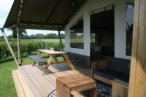 Porche de tienda safari con muebles de madera en Farm Campsite the Katreel, Boerderijcamping het Katreel, Países Bajos.