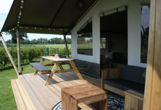 Porche de tienda safari con muebles de madera en Farm Campsite the Katreel, Boerderijcamping het Katreel, Países Bajos.