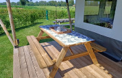 Træbord og bænk på terrasse ved safaritelte på Farm Campsite de Katreel i Holland, solrig dag.