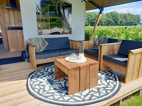 Gemütliche Holzsitzgruppe auf der Veranda eines Safari-Zeltes bei Boerderijcamping het Katreel in den Niederlanden.