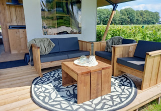 Gemütliche Holzsitzgruppe auf der Veranda eines Safari-Zeltes bei Boerderijcamping het Katreel in den Niederlanden.