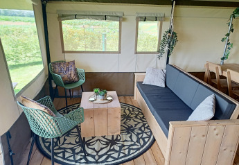 Interno di una tenda safari a Farm Campsite the Katreel nei Paesi Bassi con mobili in legno e decorazioni.