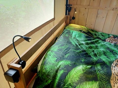 Indvendigt billede af en safari-telt med sengetøj med bregnemønster på Farm Campsite the Katreel, Holland.
