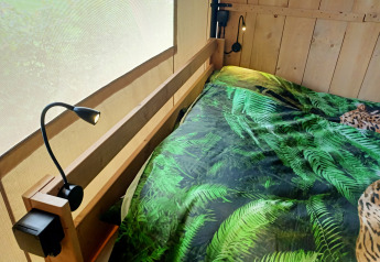 Indvendigt billede af en safari-telt med sengetøj med bregnemønster på Farm Campsite the Katreel, Holland.