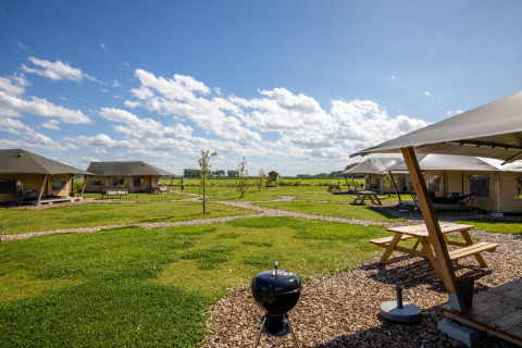 Tiendas glamping con mesas de picnic y barbacoa en FarmCamps De Kamperhoek, parque vacacional en Zeeland, Países Bajos