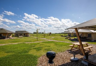 Glamping tents with picnic tables and grill at FarmCamps De Kamperhoek holiday park in Zeeland, Netherlands