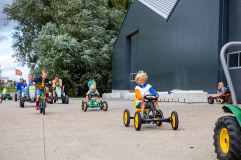 Niños jugando en karts a pedales en FarmCamps De Kamperhoek, parque vacacional en Zeeland, Países Bajos.