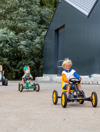 Niños jugando en karts a pedales en FarmCamps De Kamperhoek, parque vacacional en Zeeland, Países Bajos.