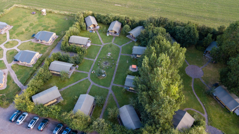 Vista aérea del parque vacacional FarmCamps De Kamperhoek en Zelanda, Países Bajos, con cabañas rodeadas de césped.