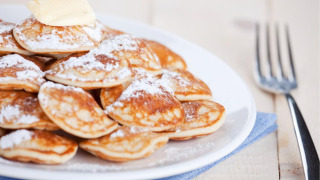 Een bord poffertjes met poedersuiker en boter op FarmCamps De Oostermaat in Overijssel, Nederland.
