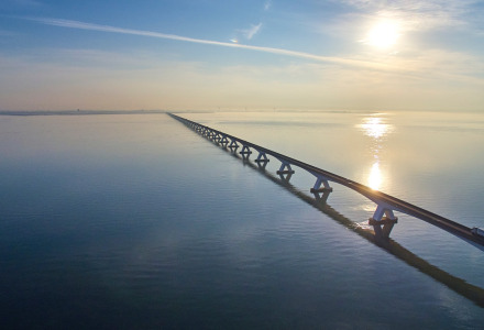 Vista de un largo puente sobre aguas tranquilas cerca de Vogelwaarde, Zelanda, Países Bajos, bajo el sol.