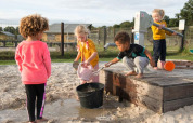 Kinder spielen mit Wasser und Sand bei einer Pumpe im FarmCamps Alpaca Vorstenbosch, Nordbrabant, Niederlande.