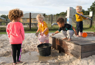 Children play with water and sand at a pump in FarmCamps Alpaca Vorstenbosch, North Brabant, Netherlands.