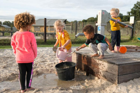 Kinder spielen mit Wasser und Sand bei einer Pumpe im FarmCamps Alpaca Vorstenbosch, Nordbrabant, Niederlande.